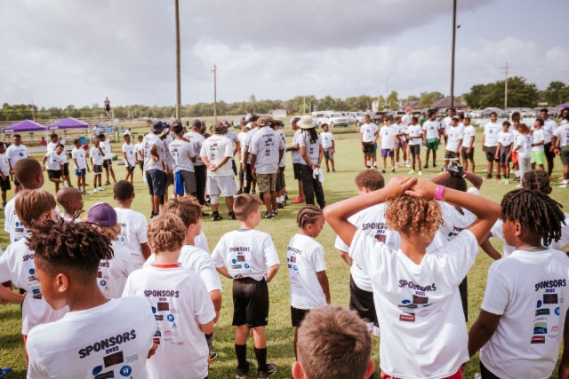 The team gathers as the kids look on at Patrick Queen 2022 "level Up" youth football camp
